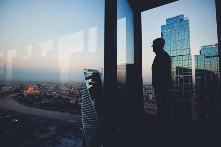 Wide angle contrast shot of person looking out over London skyline in high-rise skyscraper building at dusk