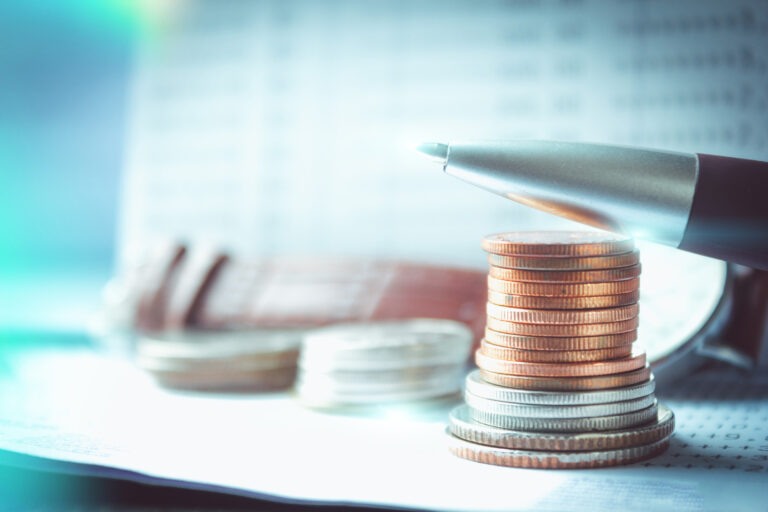Close up of pen and stack of coins