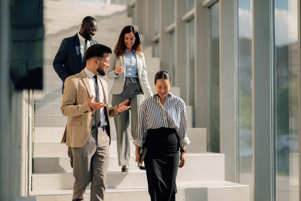 Group of multi ethnic businesspeople descending stairs in office